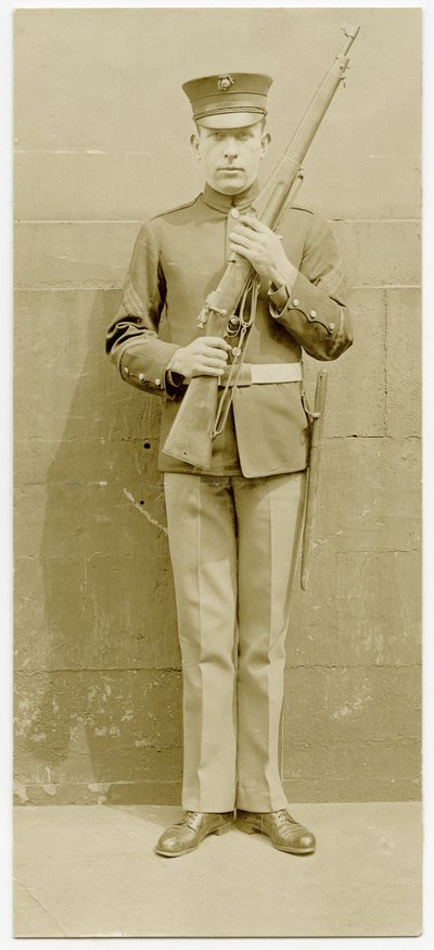 Soldato in uniforme che posa per una foto davanti a un muro di cemento da Carl Michel